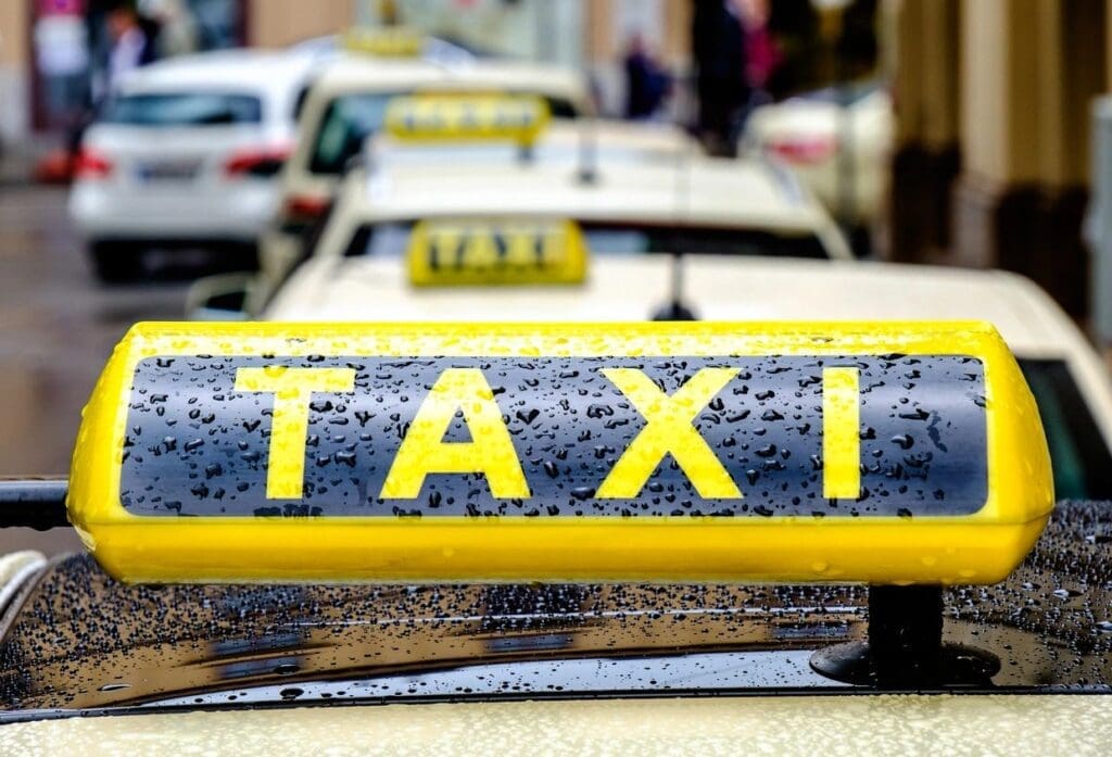 Close-up of a yellow taxi sign covered in raindrops.