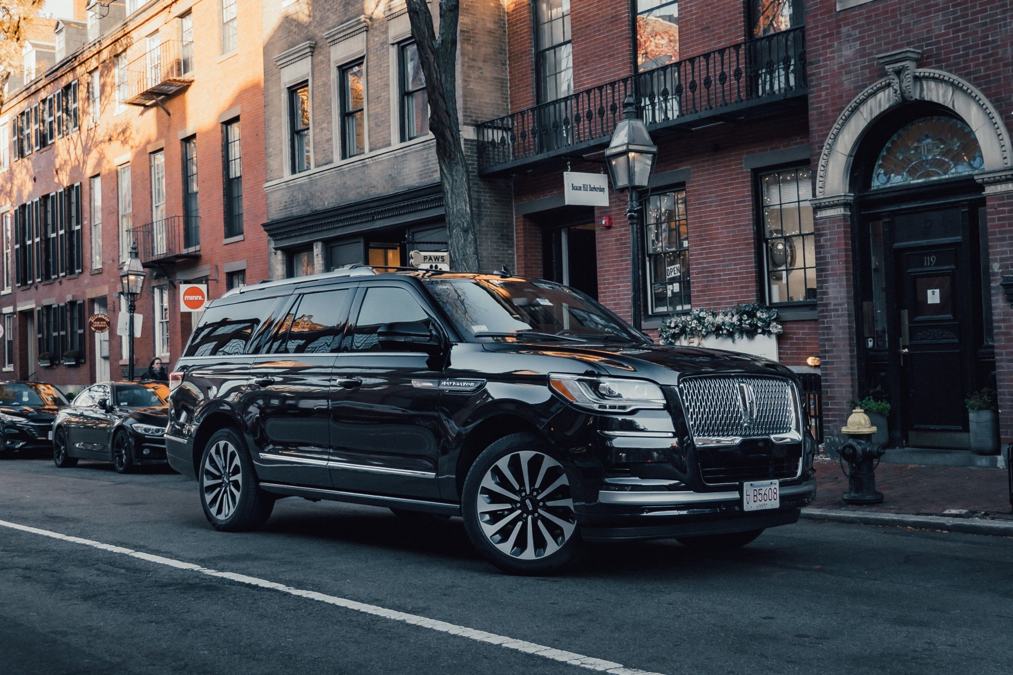 Luxury black SUV parked on a city street in front of brownstone buildings.