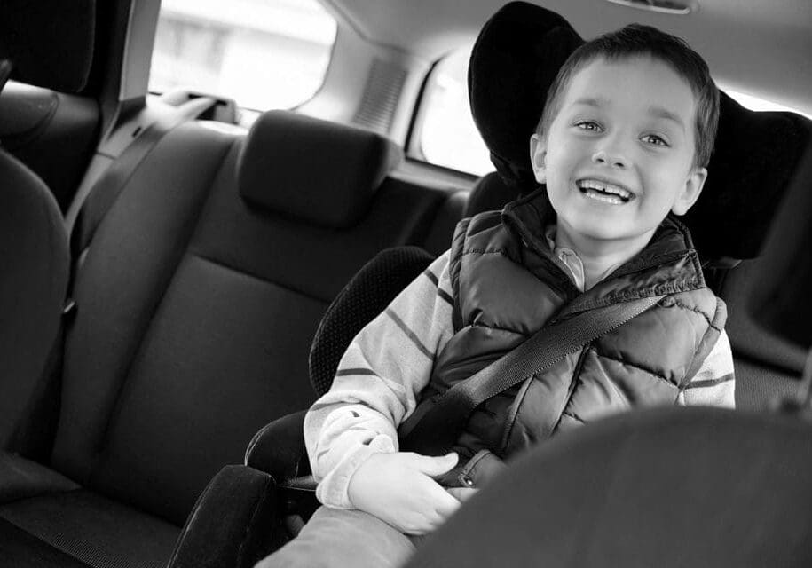 A young boy sitting in the back of a car.